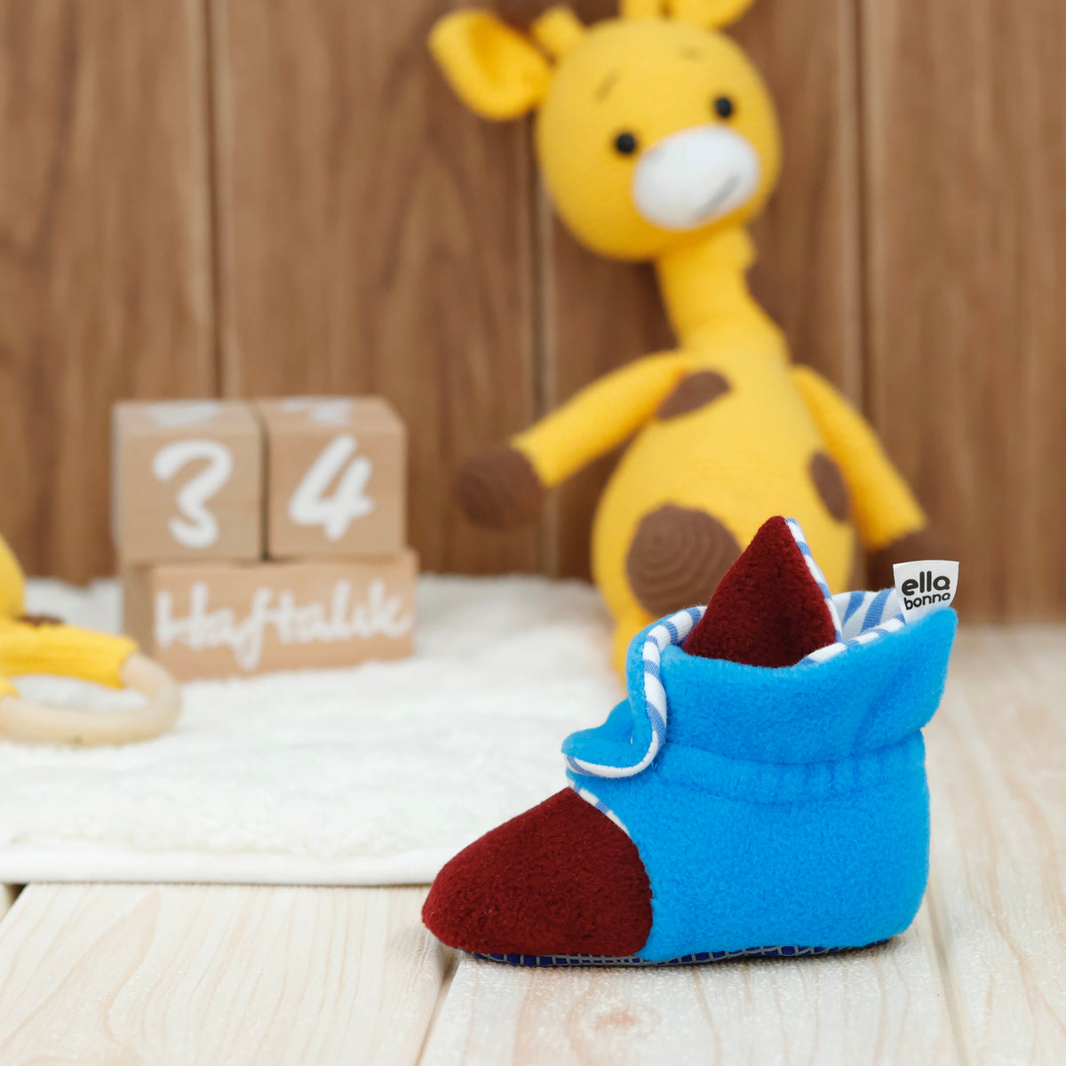 Single bootie on a tabletop beside toy giraffes.