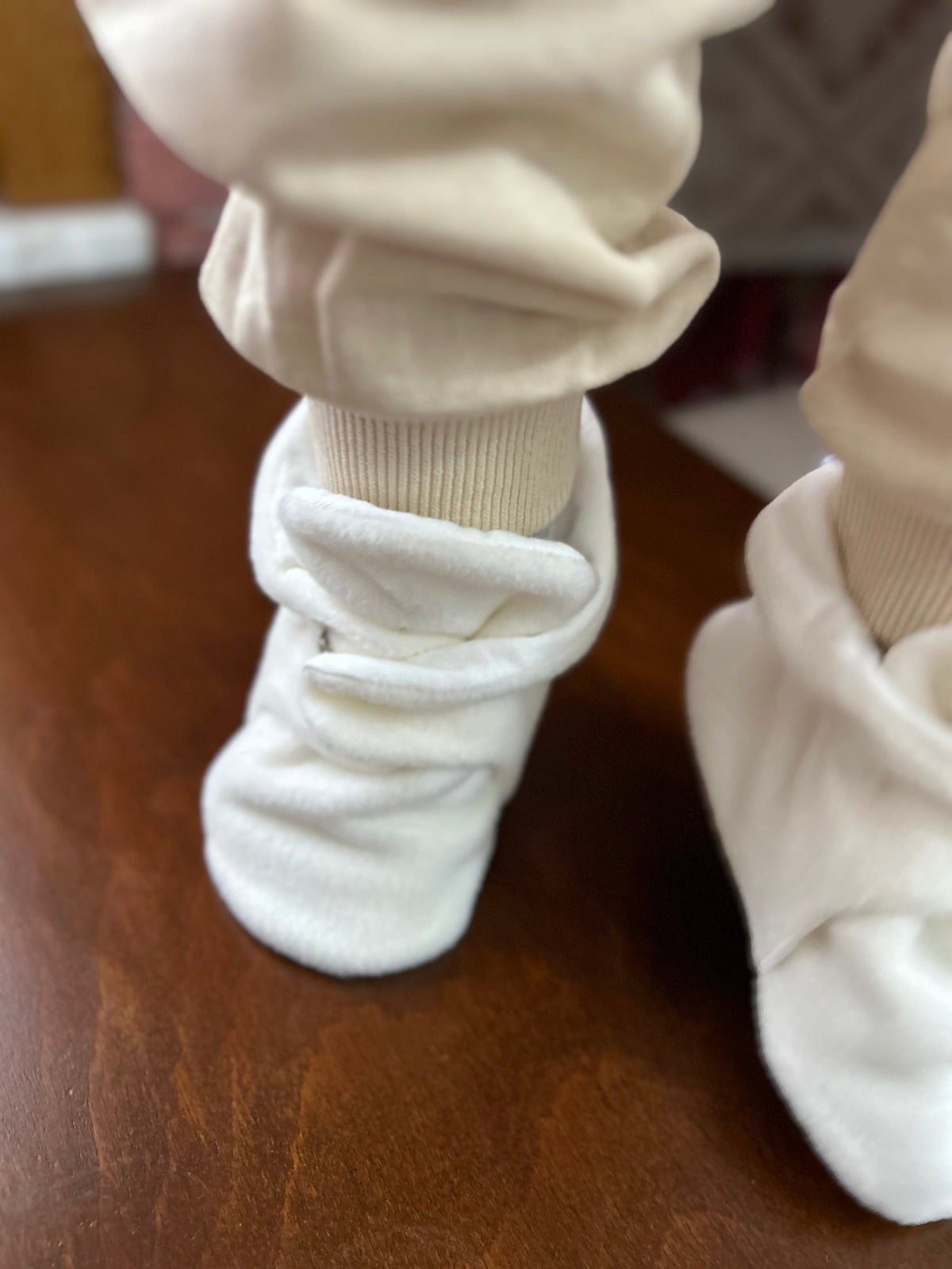 Close-up of white booties worn with cream trousers.