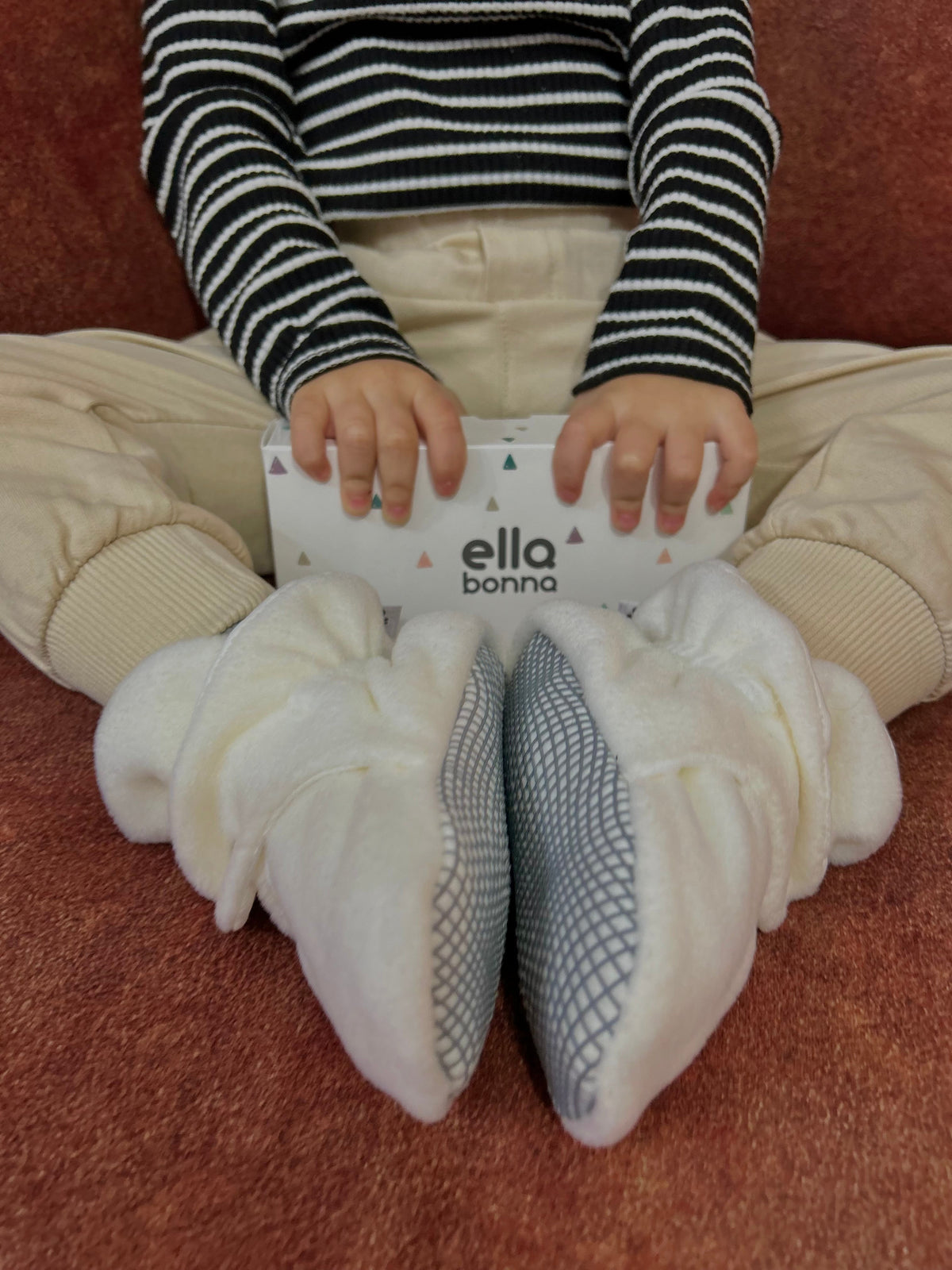 Child holding an Ella Bonna card with the gray bootie soles visible.