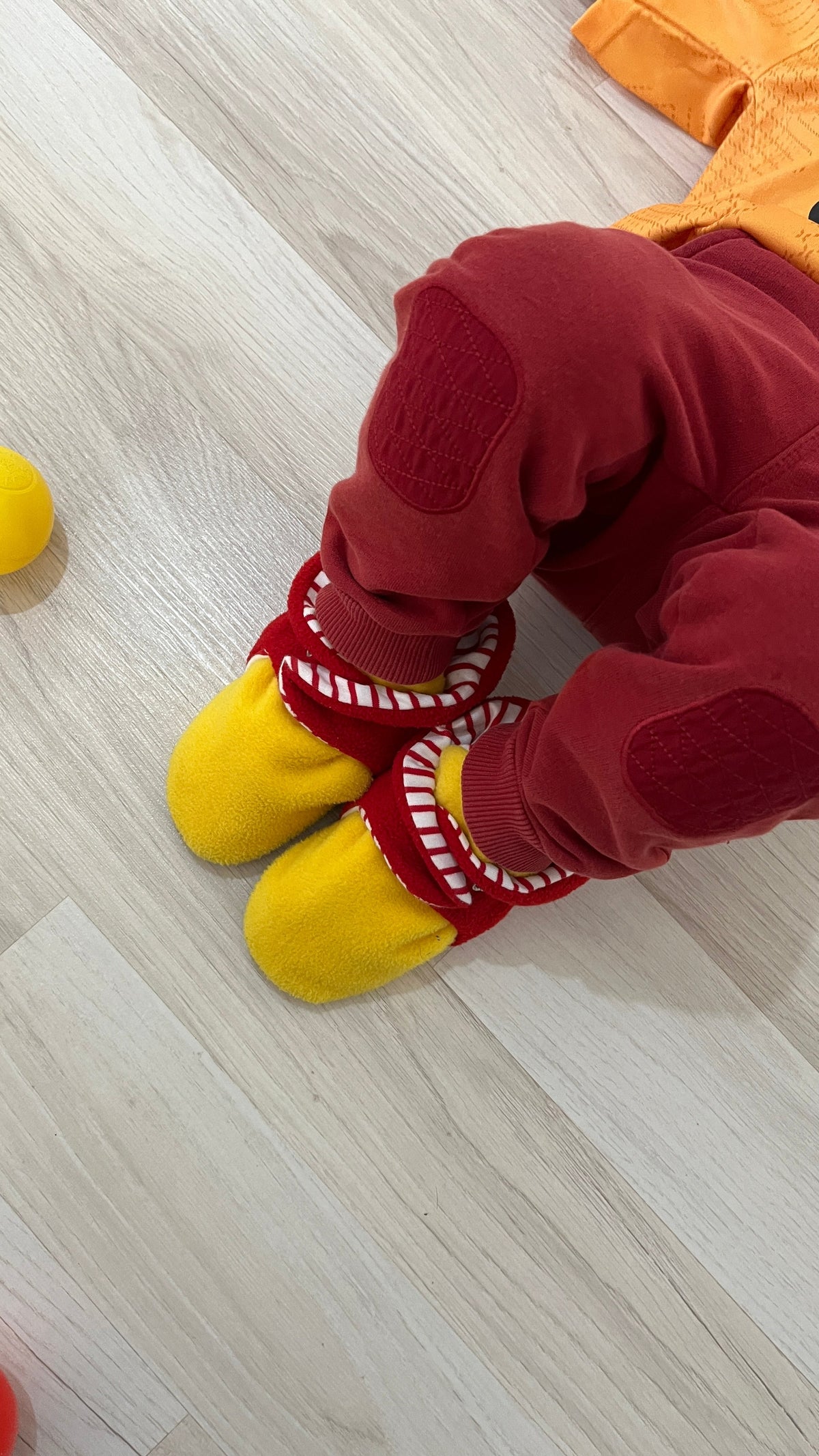 Close-up of red-and-yellow booties worn with burgundy trousers.