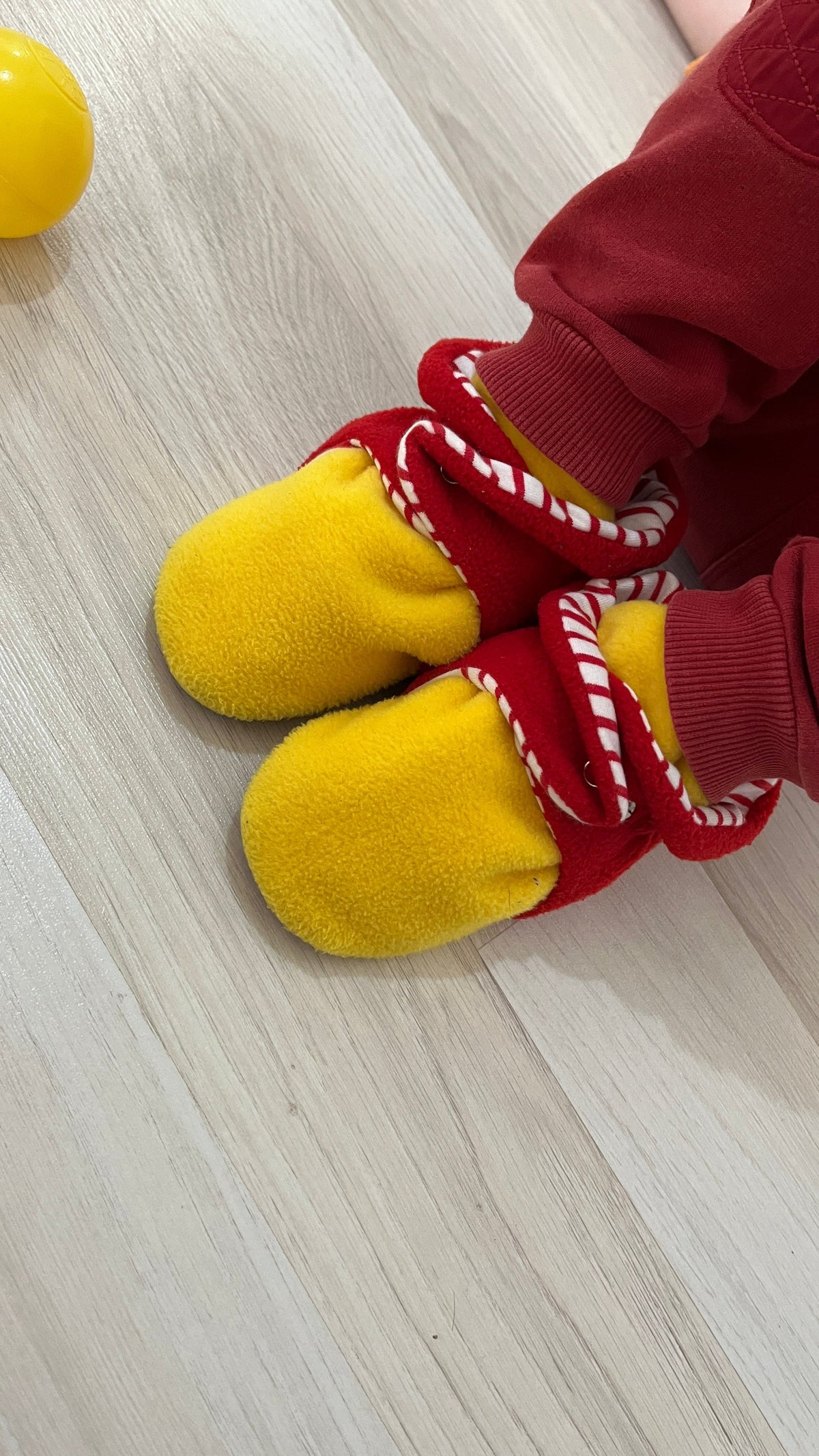 Overhead close-up of red-and-yellow booties worn with burgundy trousers.