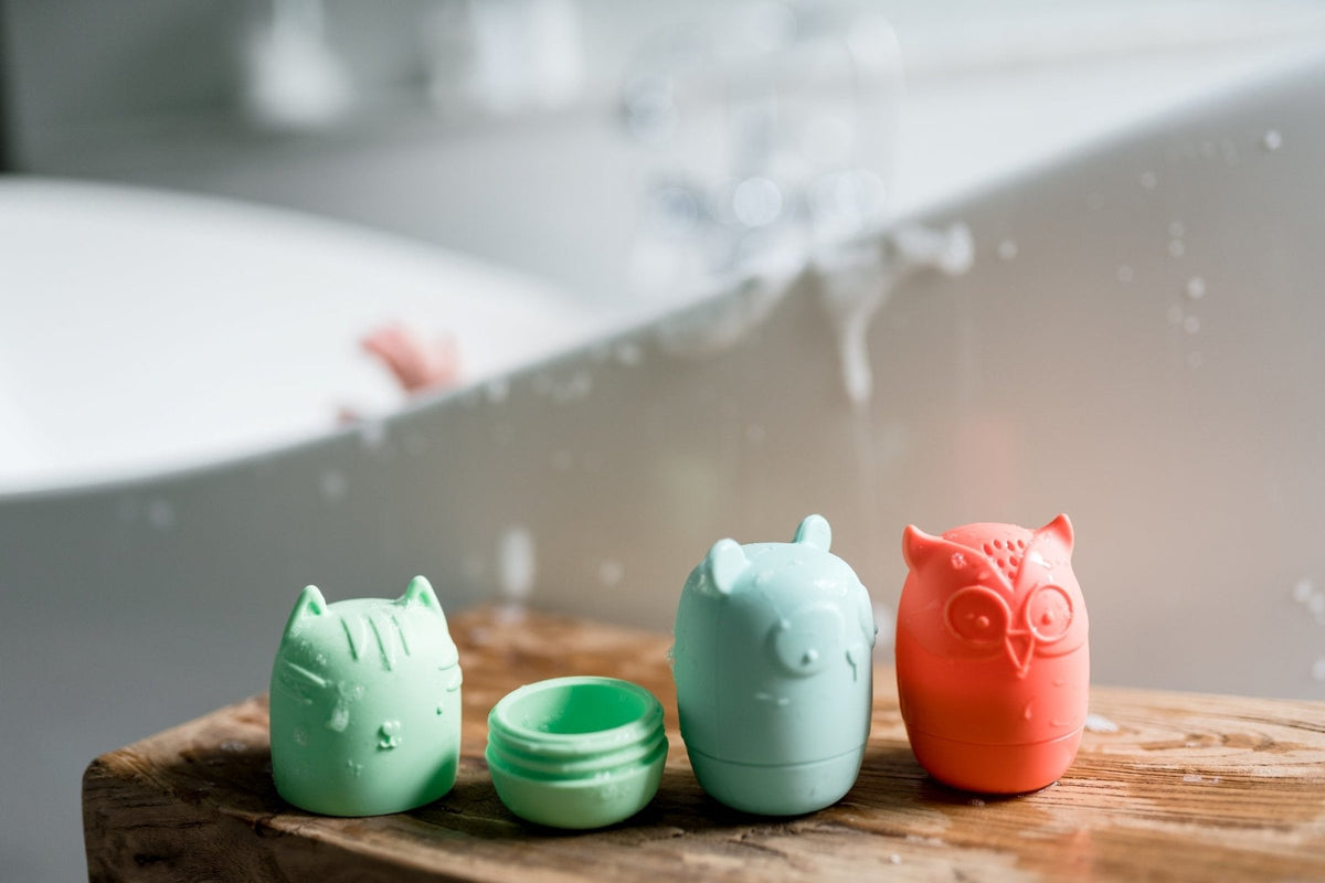 Silicone Bath Buddies on a wooden surface, including one opened toy showing its interior