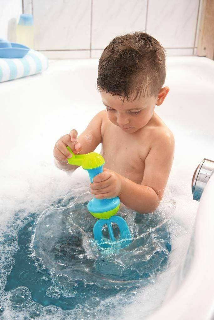 A child holding the blue and lime green HABA Bubble Bath Whisk upright in bath water