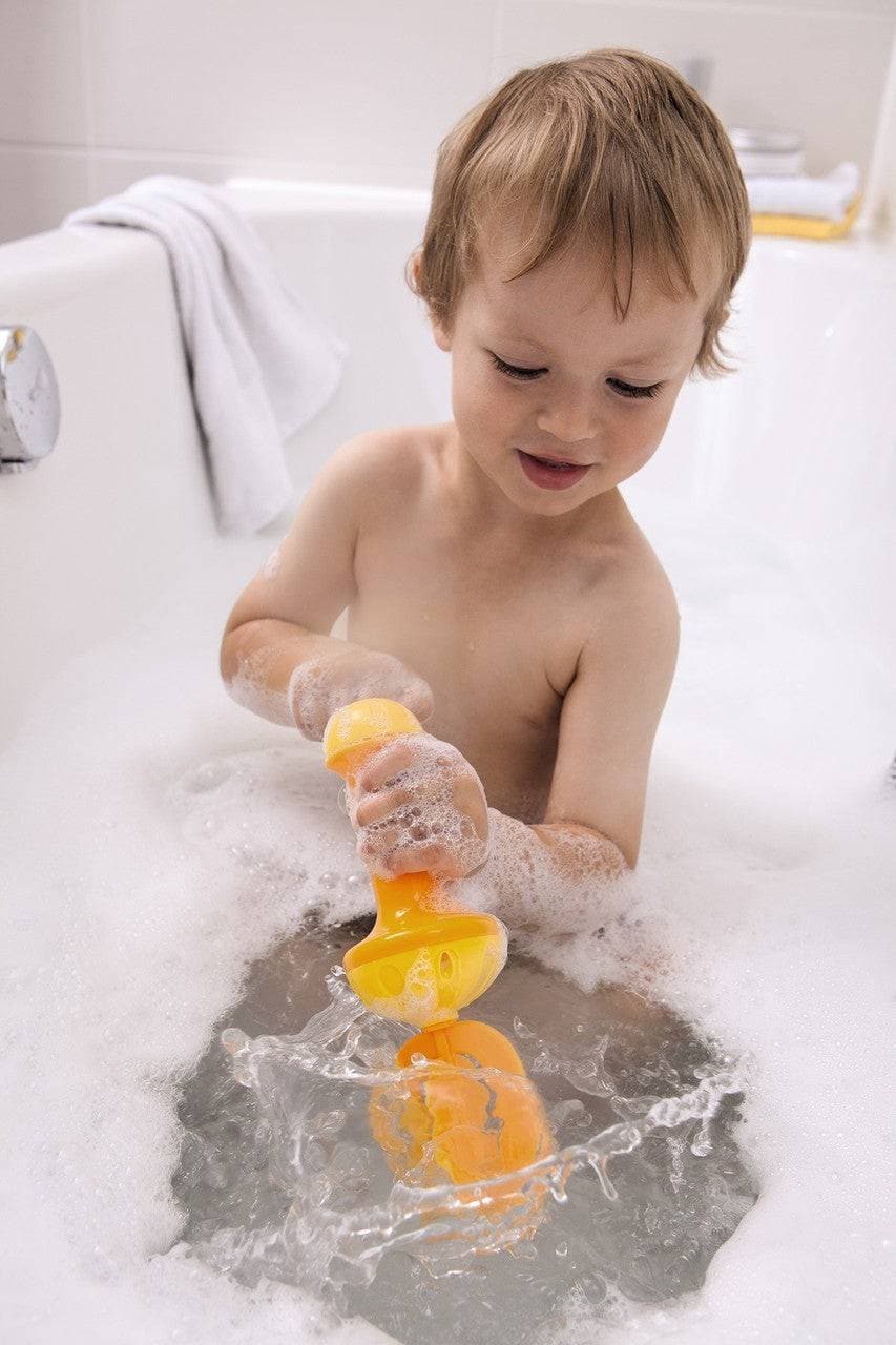 A child using the yellow HABA Bubble Bath Whisk in a bubbly bathtub