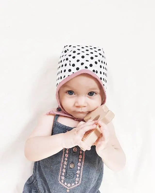 Baby holding a bunny-shaped wooden grasping toy without visible silicone beads
