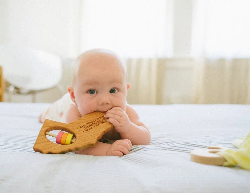 Lifestyle photo showing a wooden state rattle with a child