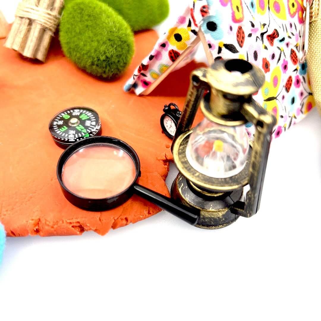 Miniature lantern, compass and magnifying glass beside the Camping Trip tent