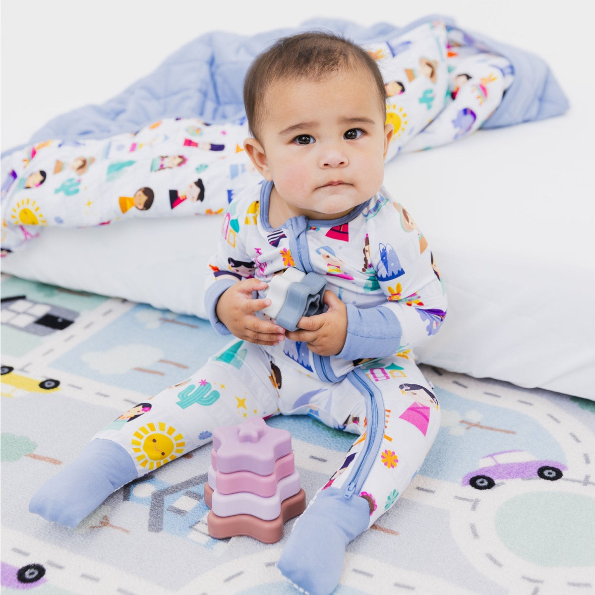 Baby playing while seated in Bam & Stitch Children of the World Convertible Romper.