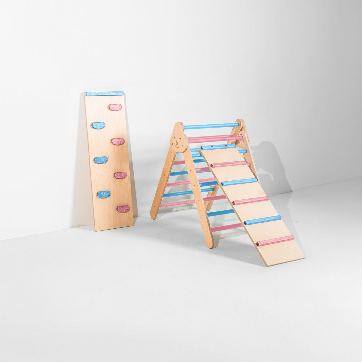 Pastel blue and pink triangle with attached ladder ramp and a climbing-hold ramp beside it.