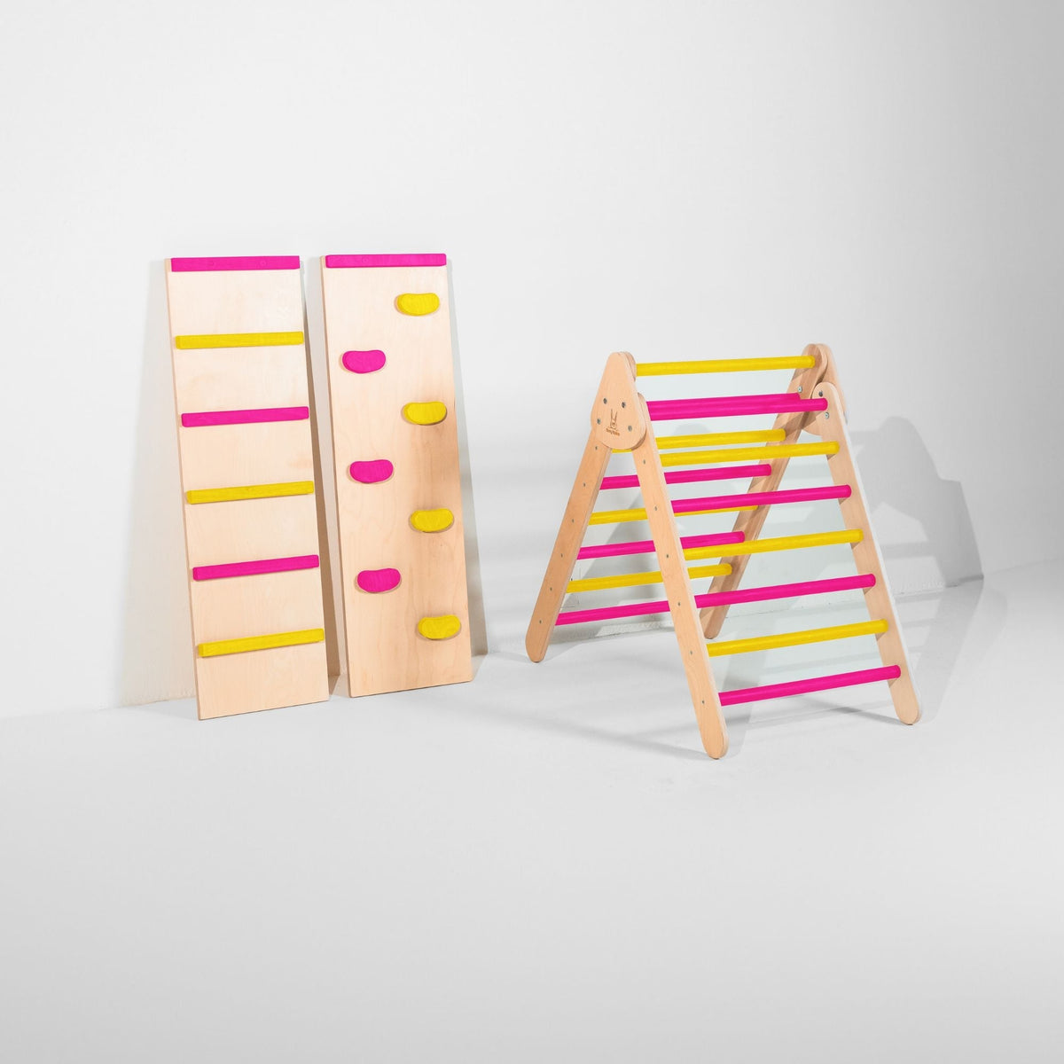 Classic Climber triangle with bright pink and yellow rungs beside two upright ramps.