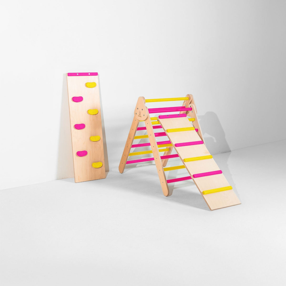 Pink and yellow triangle with attached ladder ramp and a climbing-hold ramp beside it.