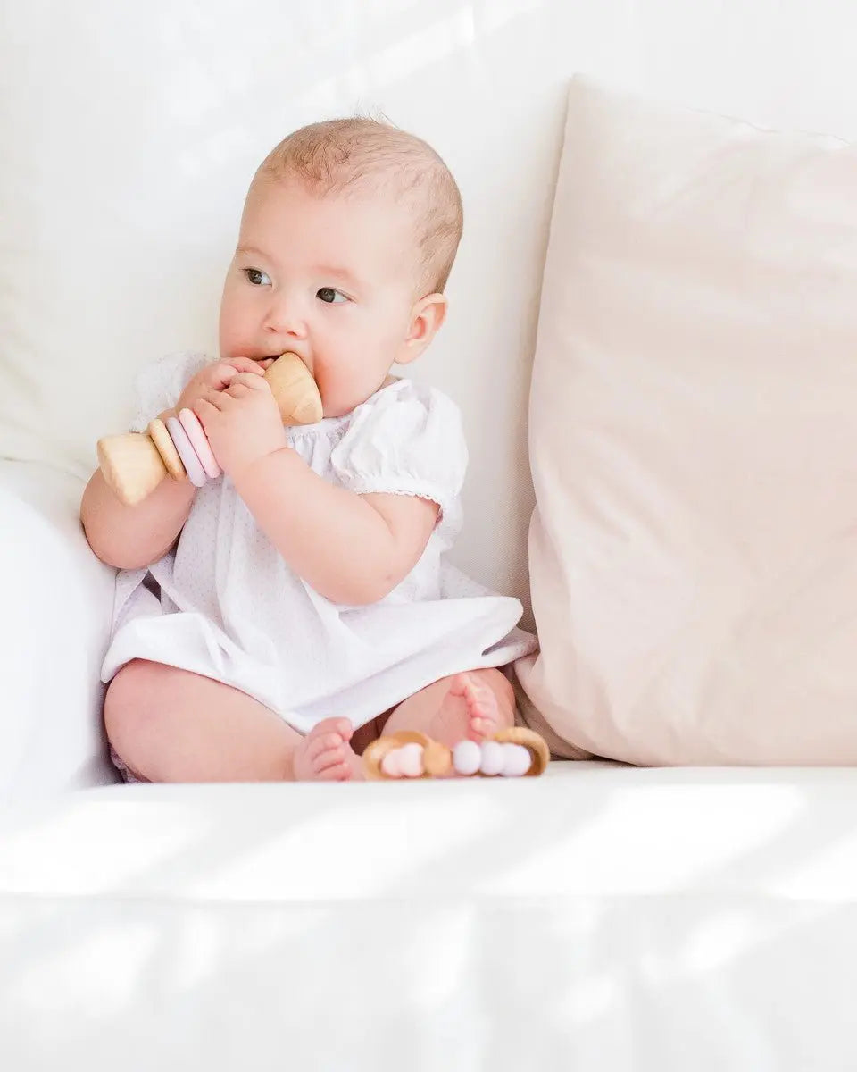 Lifestyle photo showing a wooden rattle with silicone rings with a child