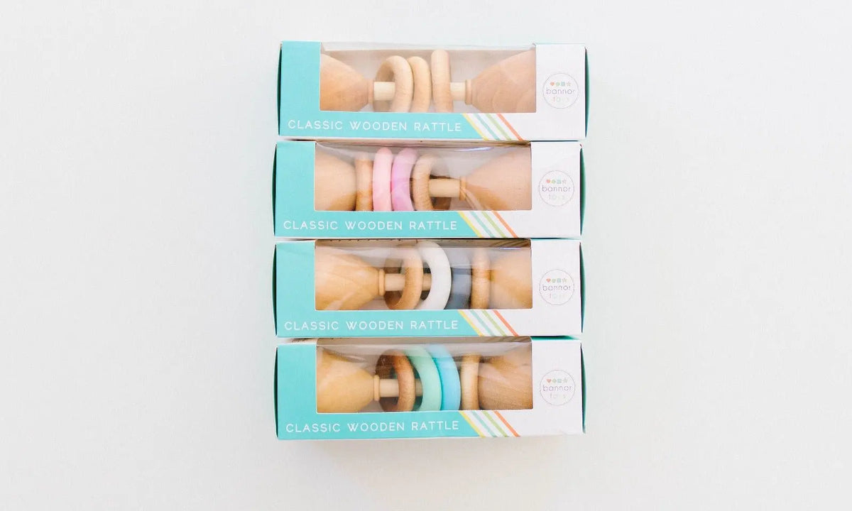 Stack of packaged Color Block baby rattles showing several silicone ring colors