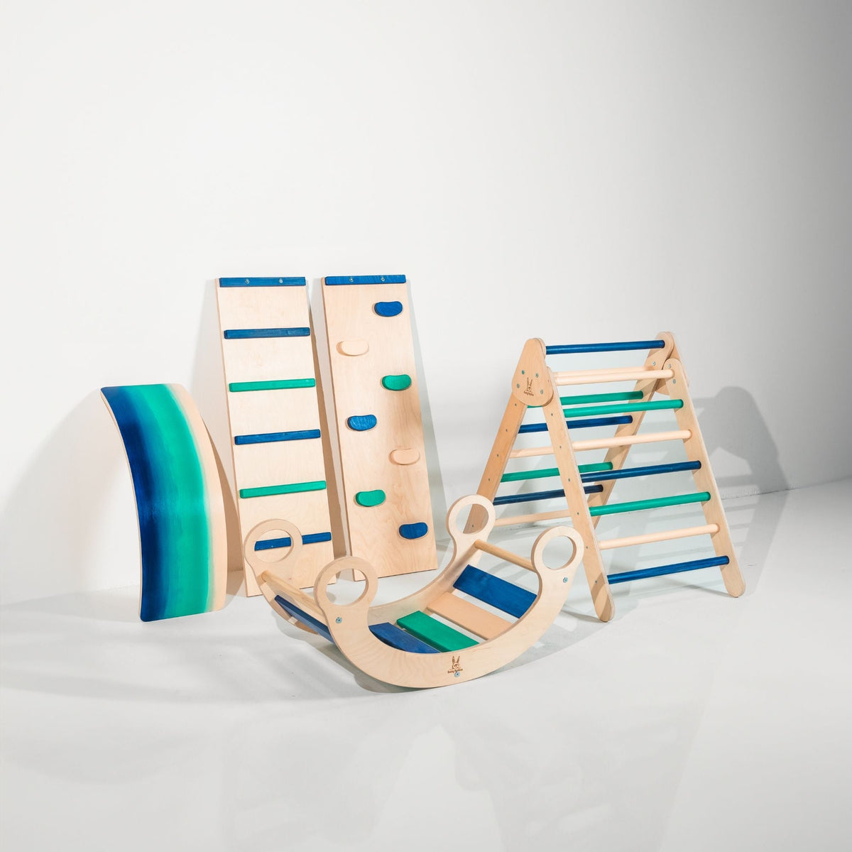 Blue and teal climbing triangle, two ramps, curved wobble board and rocker displayed together.