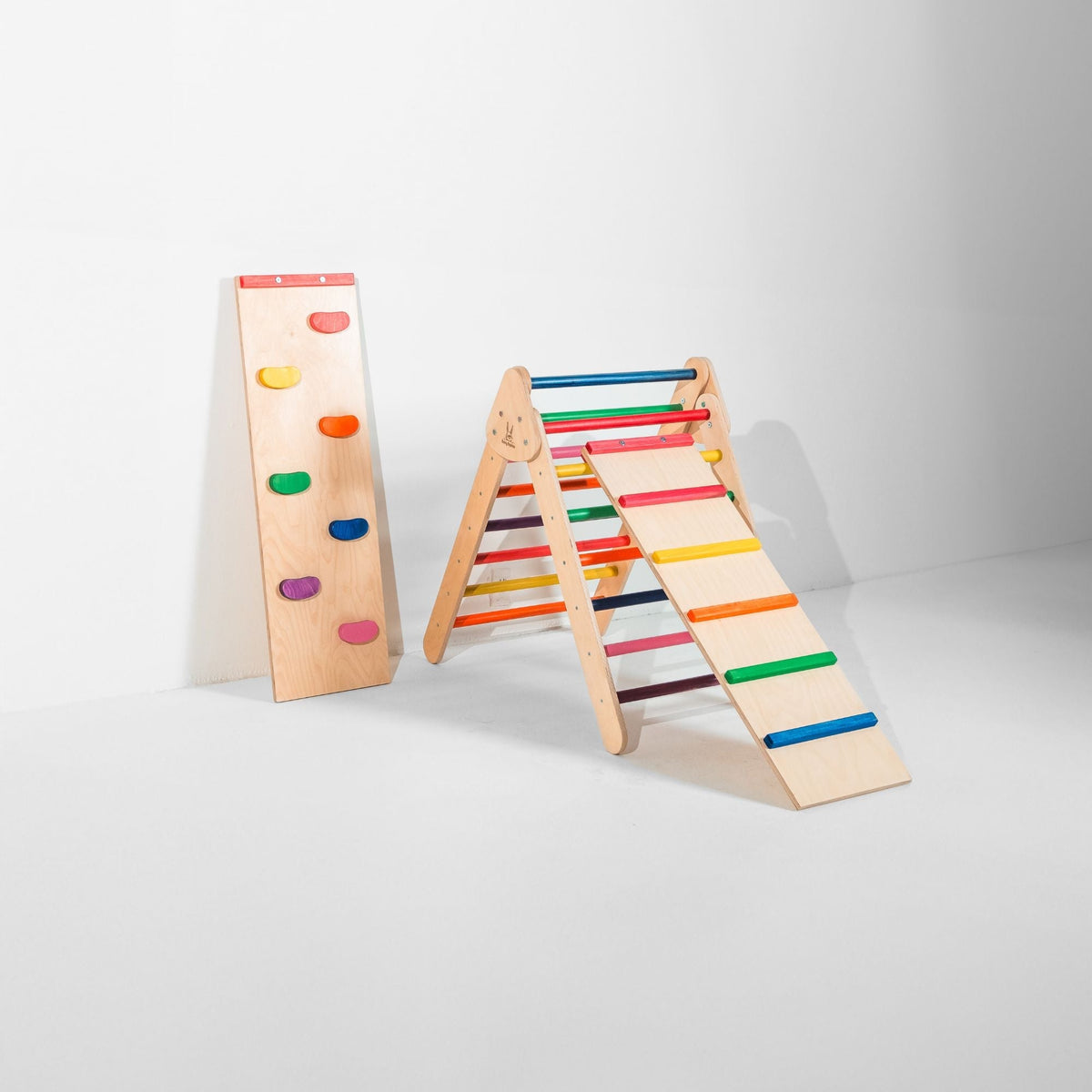 Rainbow-rung triangle with attached ladder ramp and a climbing-hold ramp beside it.