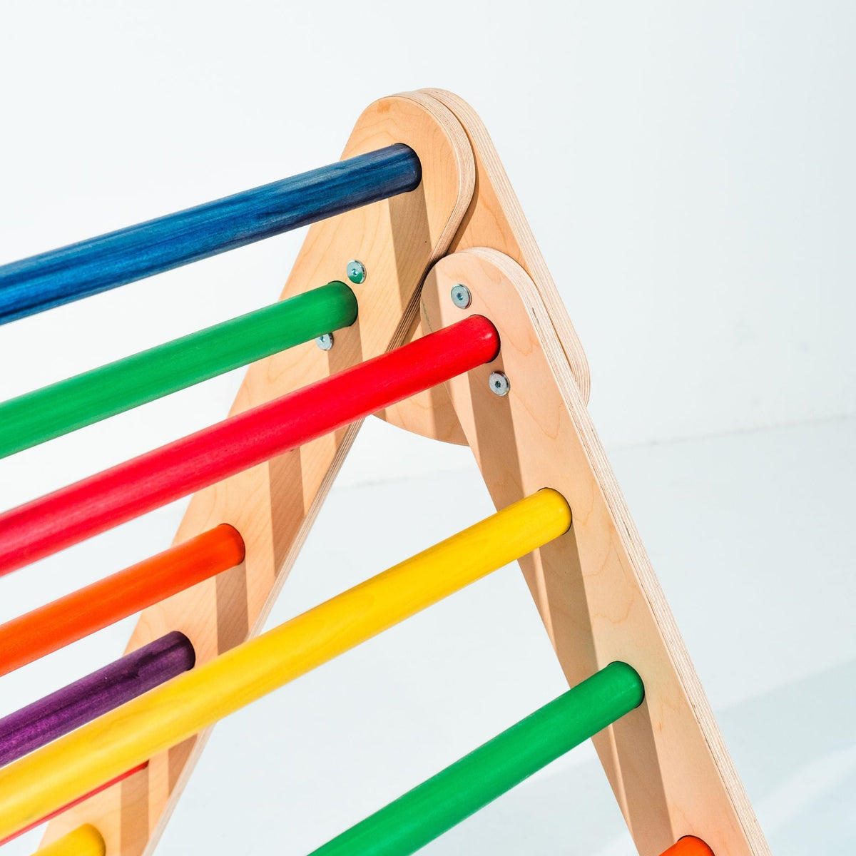 Close-up of rainbow rungs and the rounded top joint of a climbing triangle.