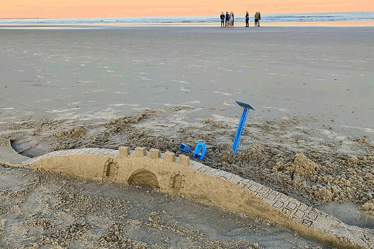 Long sand bridge with an arched opening and blue detailing tools beside it at sunset.