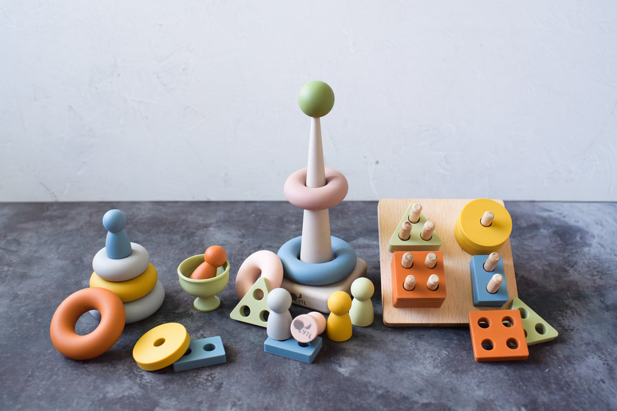 Peg dolls, ring stacker pieces, and a shape puzzle arranged in several small stacks.
