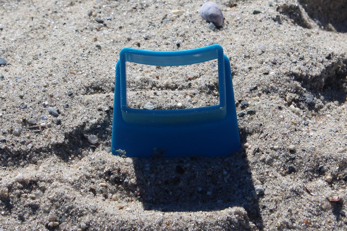 Blue rectangular battlement form standing upright on beach sand.