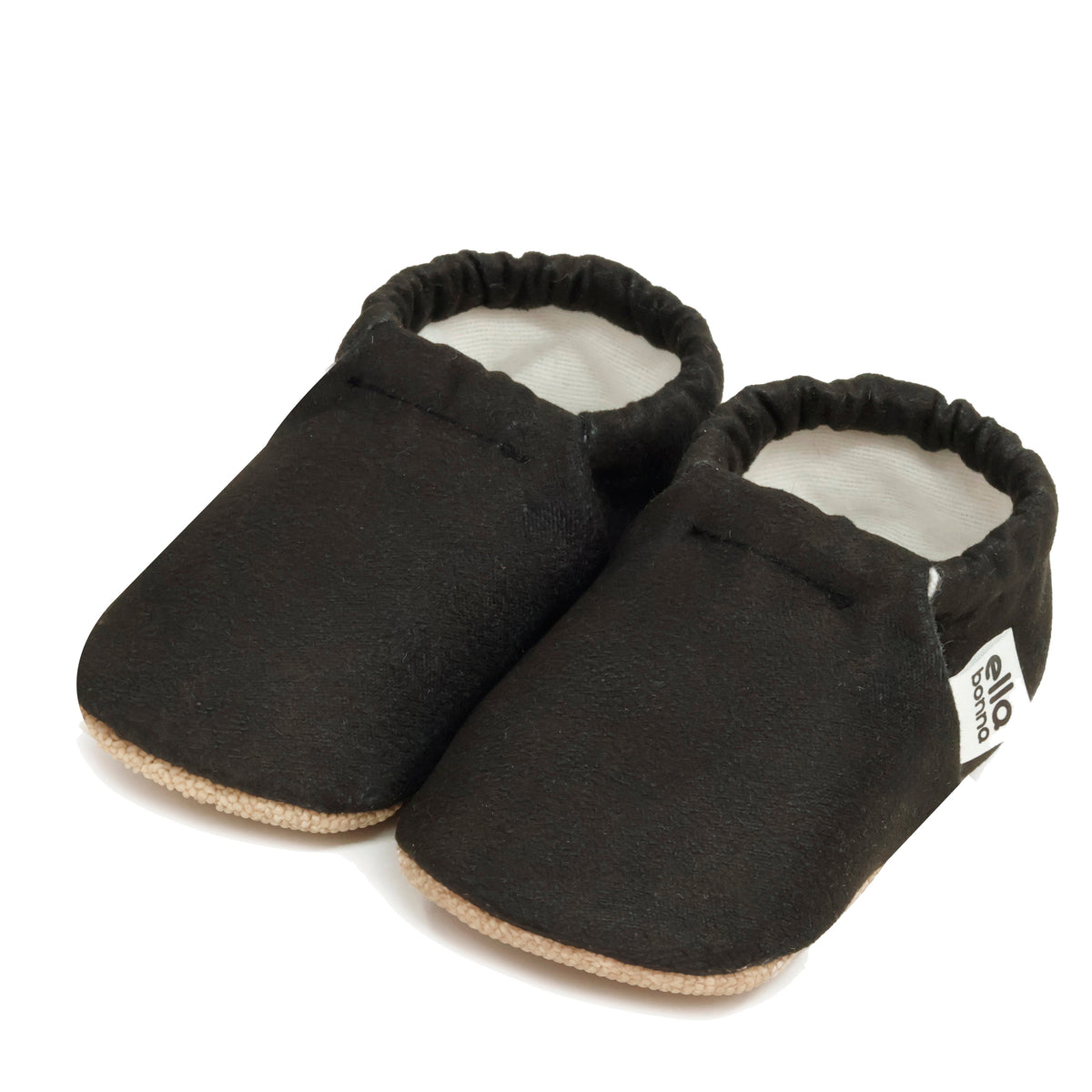 Pair of black slip-on baby moccasins with cream lining and tan soles on a white background.