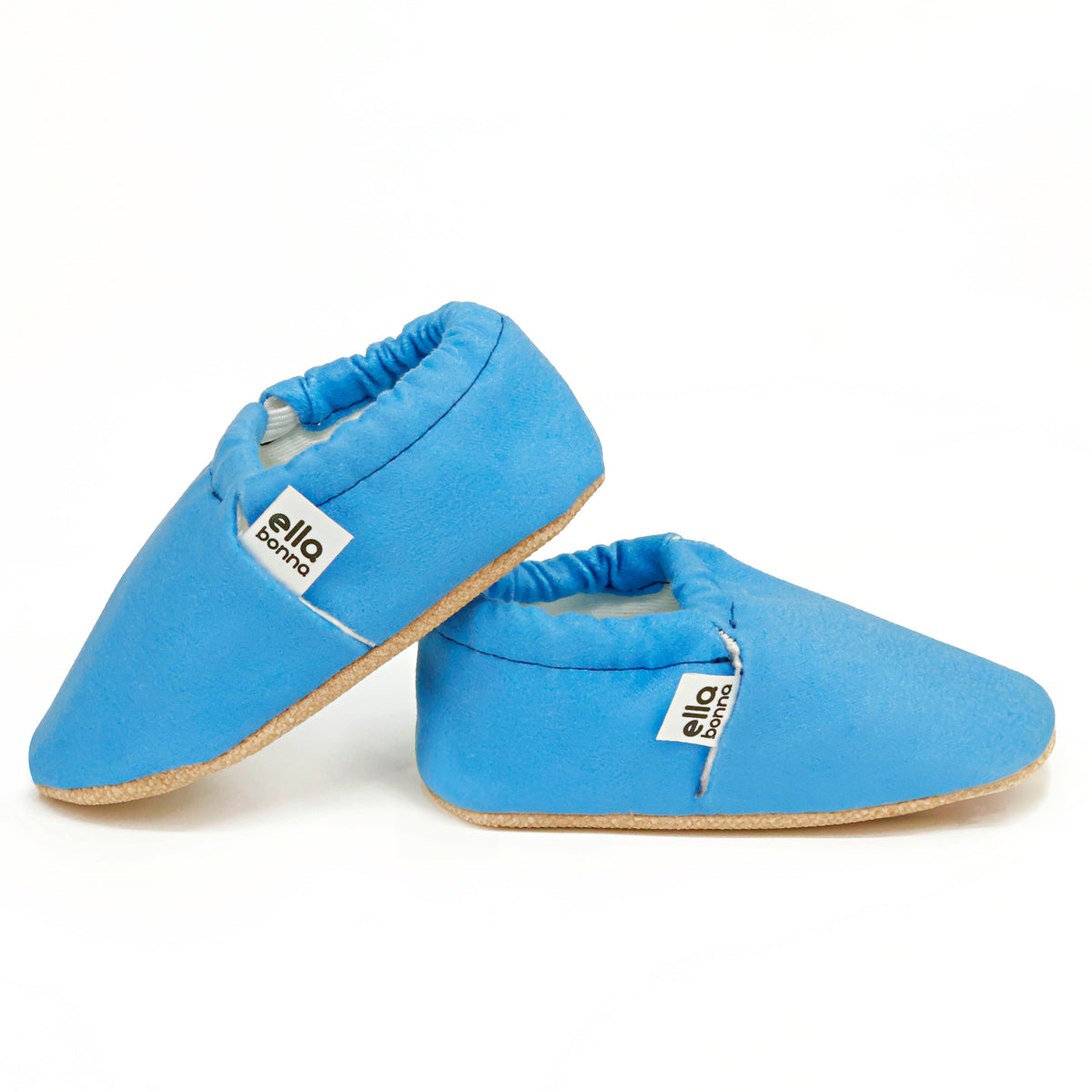 Side views of blue slip-on baby moccasins with cream lining and tan soles on a white background.