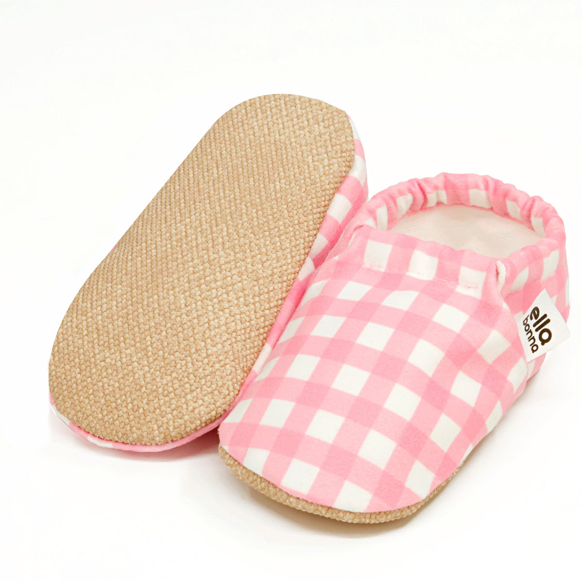 Pink-and-white gingham slip-on baby moccasins, with one sole facing the camera on a white background.