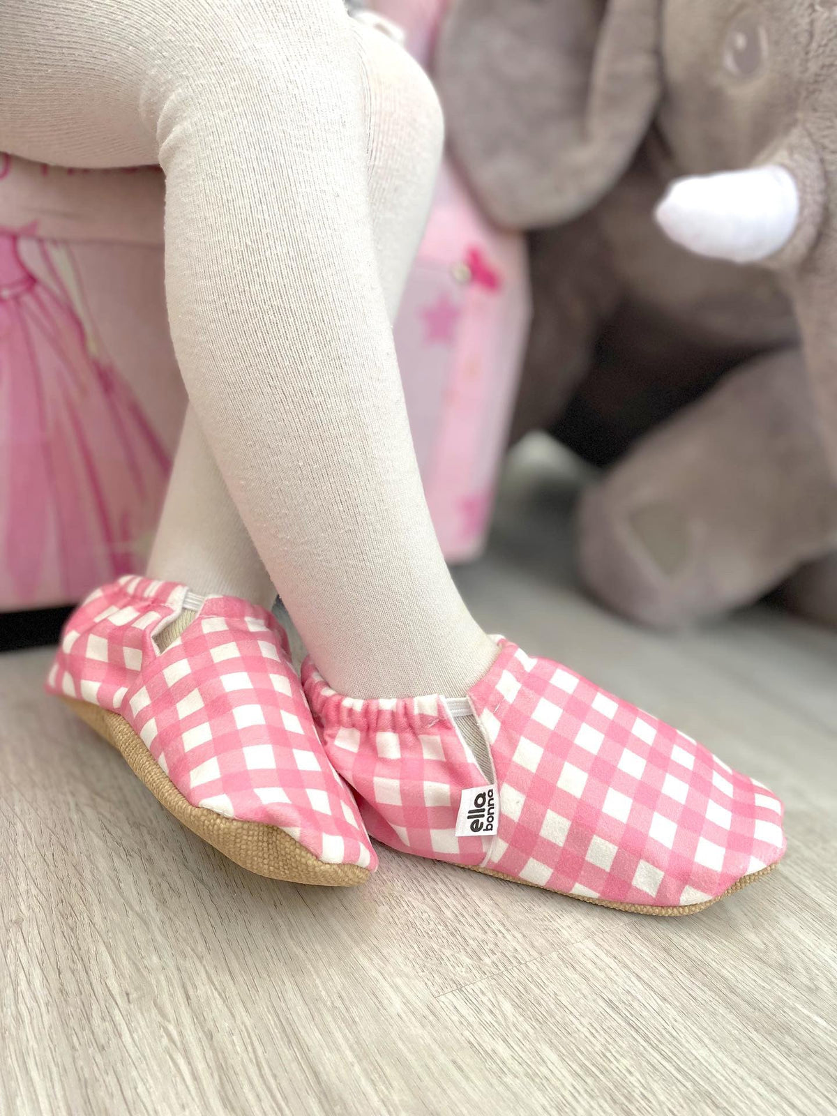 Close-up of pink gingham moccasins worn with white tights, side view.