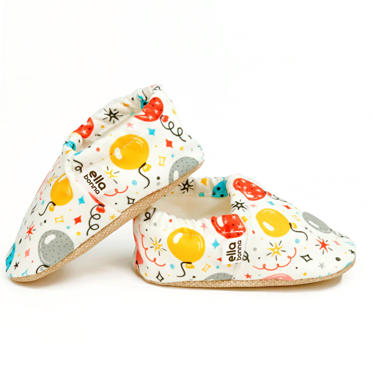 Side views of cream slip-on baby moccasins with colorful balloon print on a white background.
