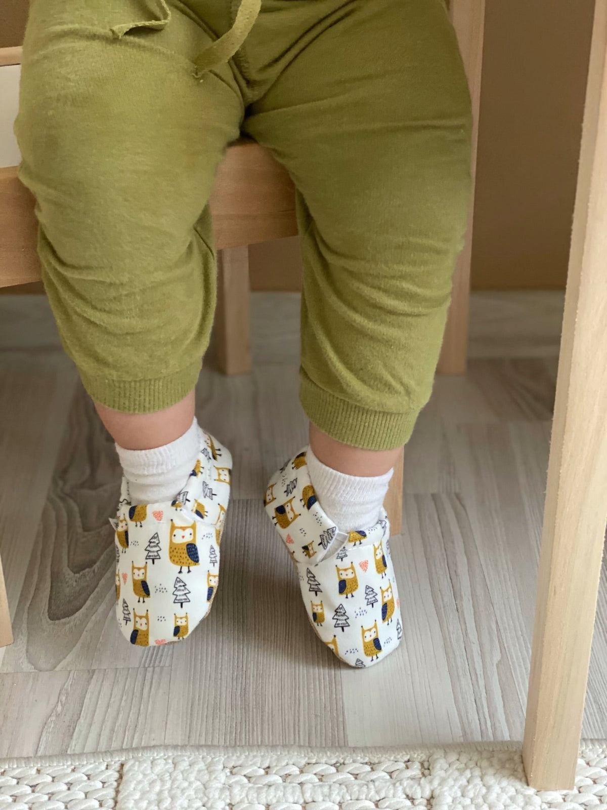 Close-up of owl-print moccasins worn with green trousers.