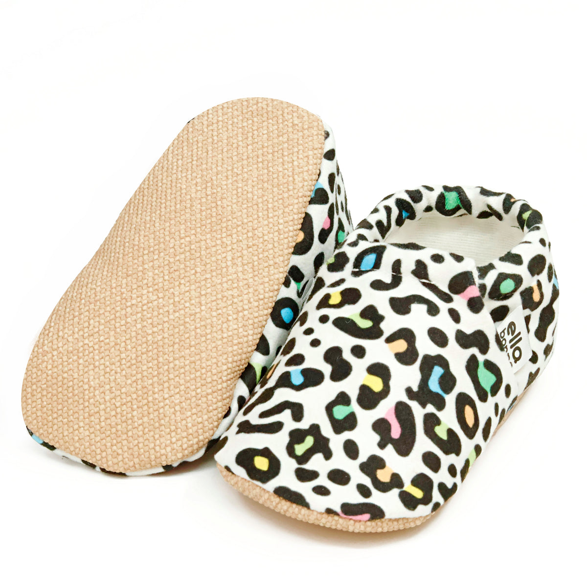 Cream slip-on baby moccasins with multicolored leopard spots, with one sole facing the camera on a white background.