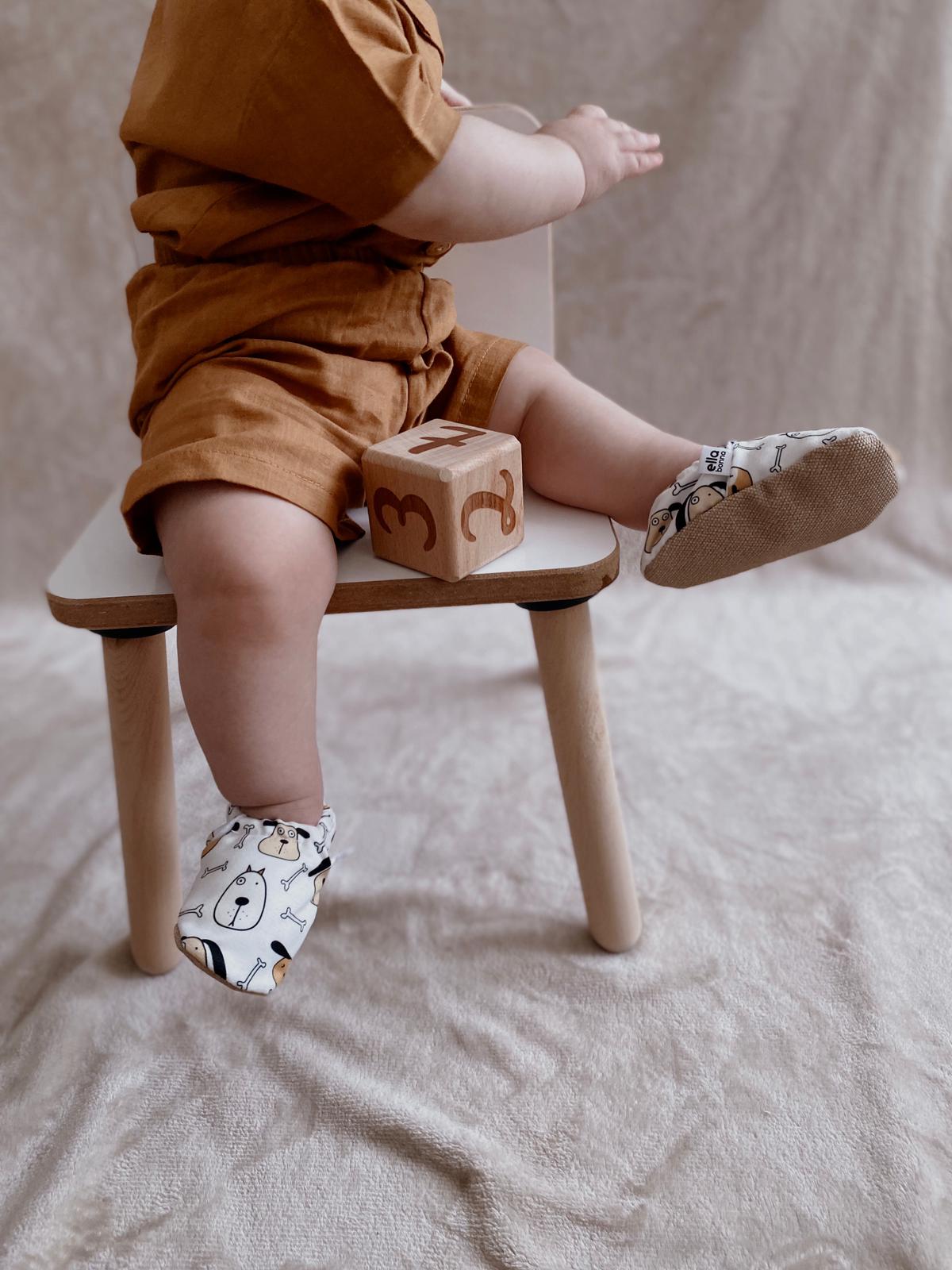 Close-up of dog-print moccasins worn by a child seated on a stool.