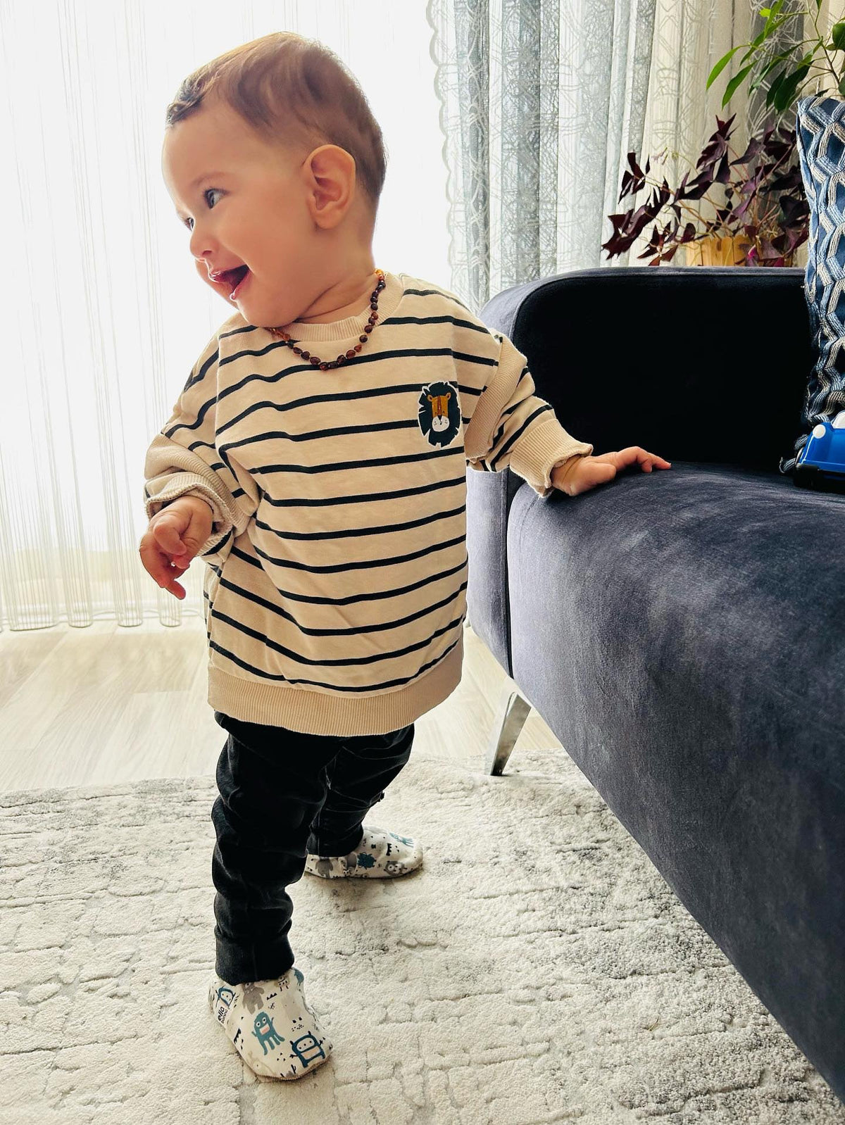 Child standing beside a sofa wearing monster-print moccasins.