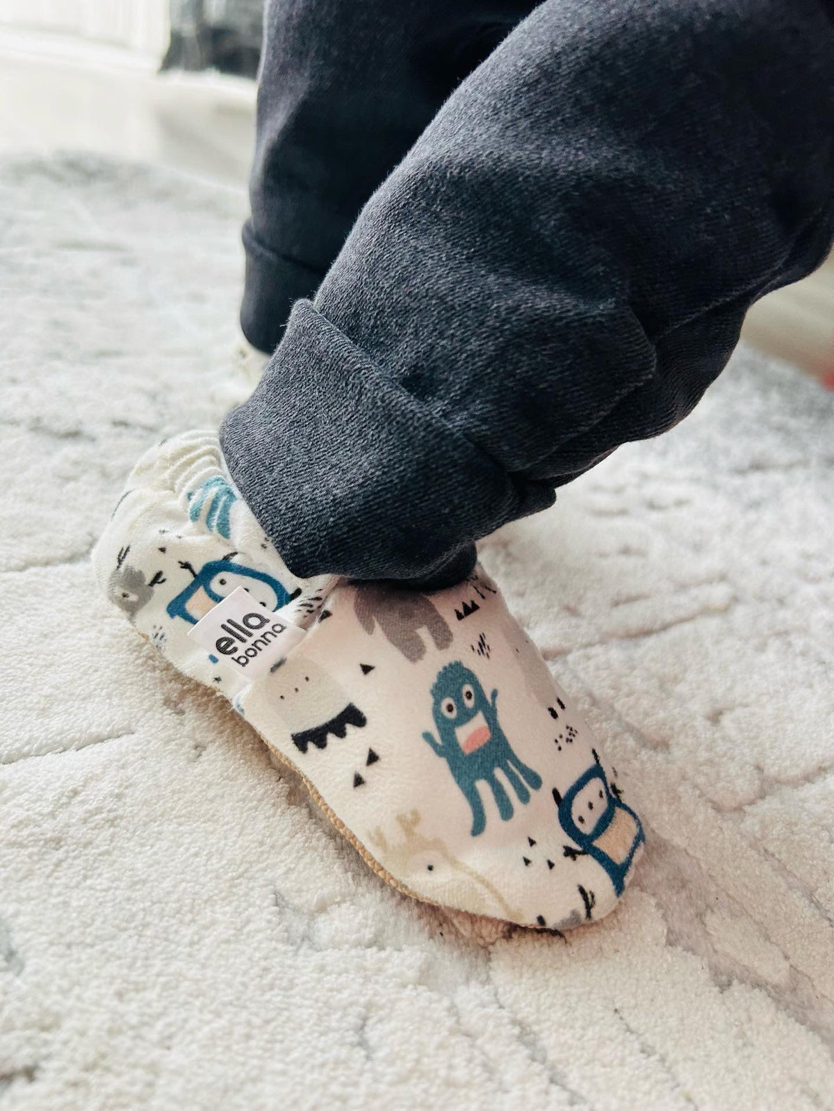 Close-up of a monster-print moccasin worn with dark trousers.
