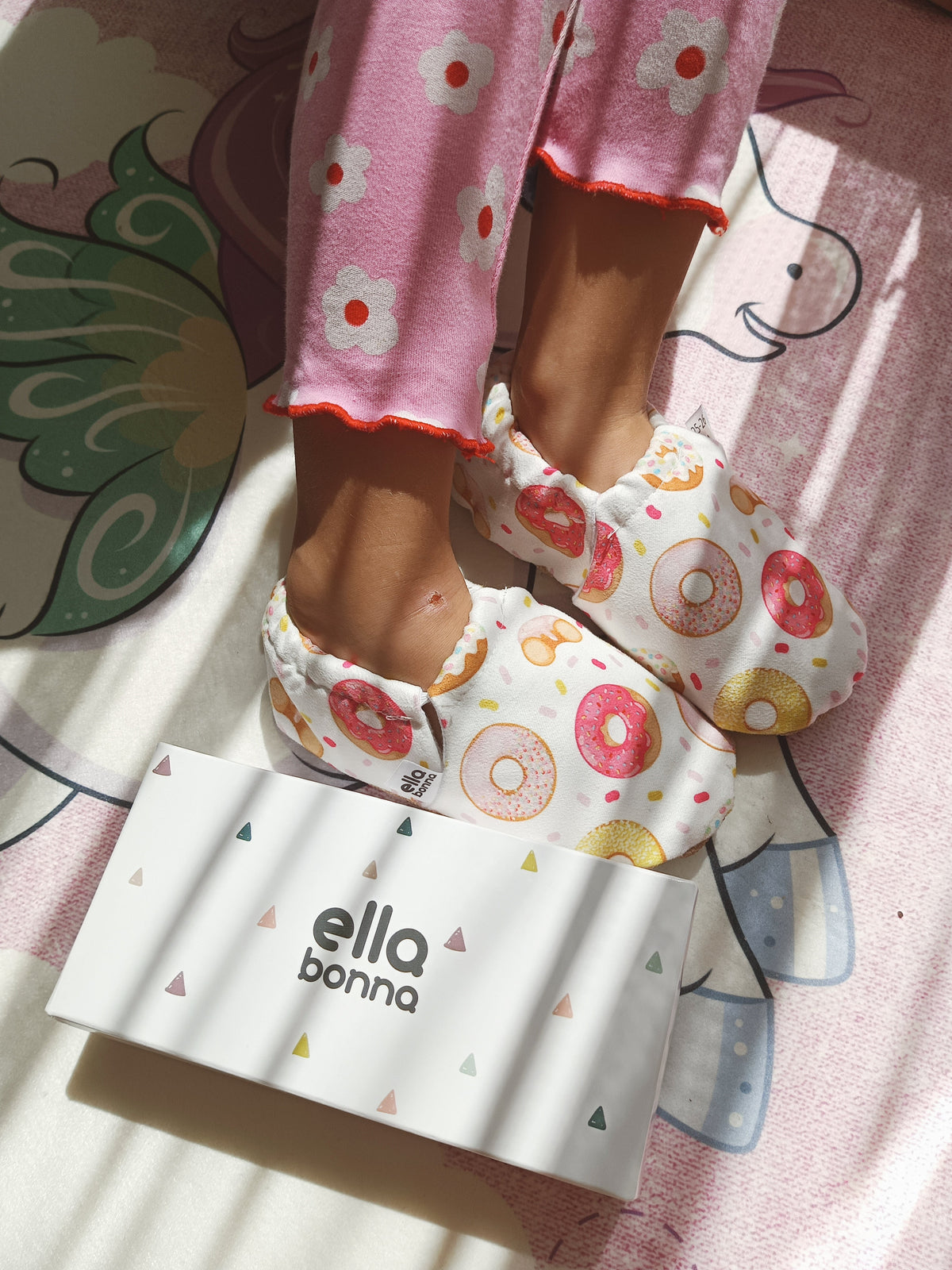 Close-up of doughnut-print moccasins beside an Ella Bonna card.