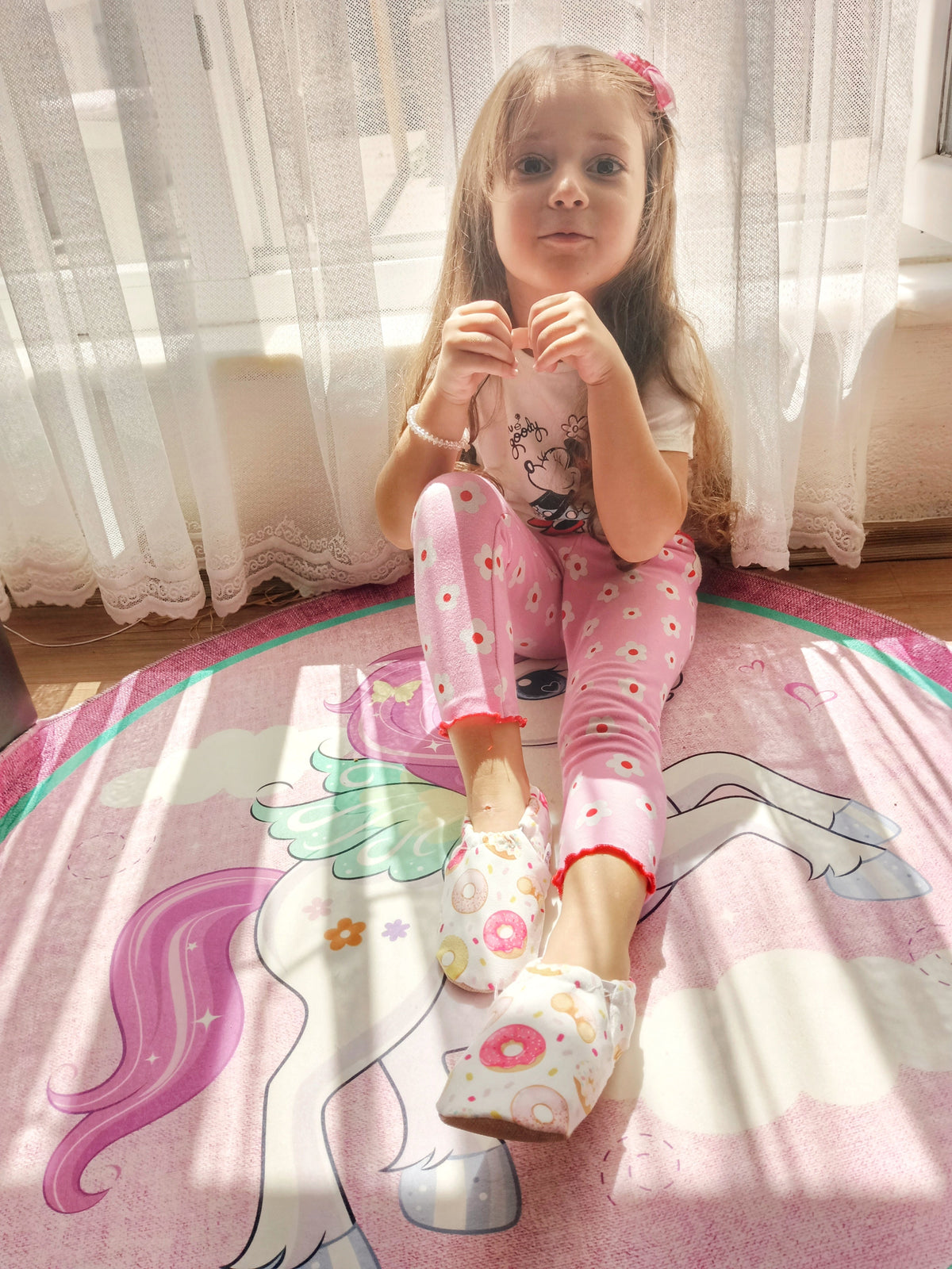 Child seated on a patterned blanket wearing doughnut-print moccasins.