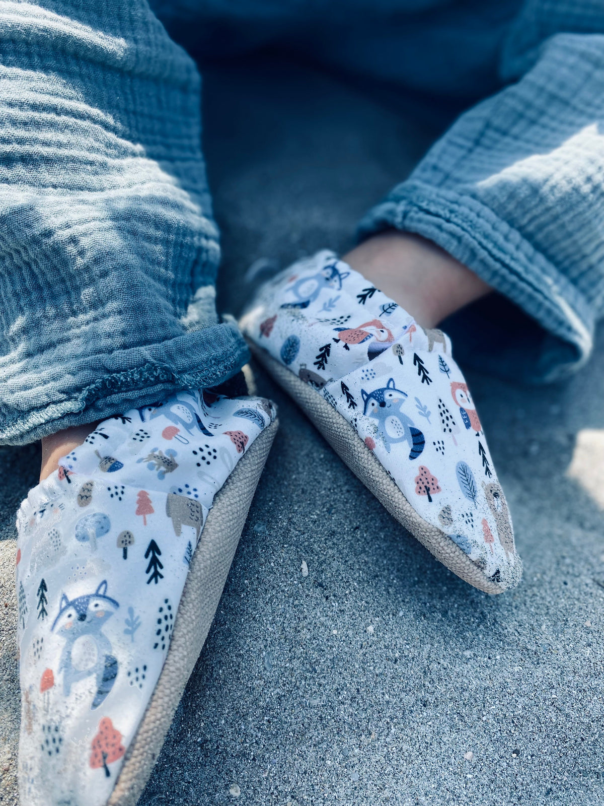 Close-up of woodland-print moccasins worn with blue trousers.