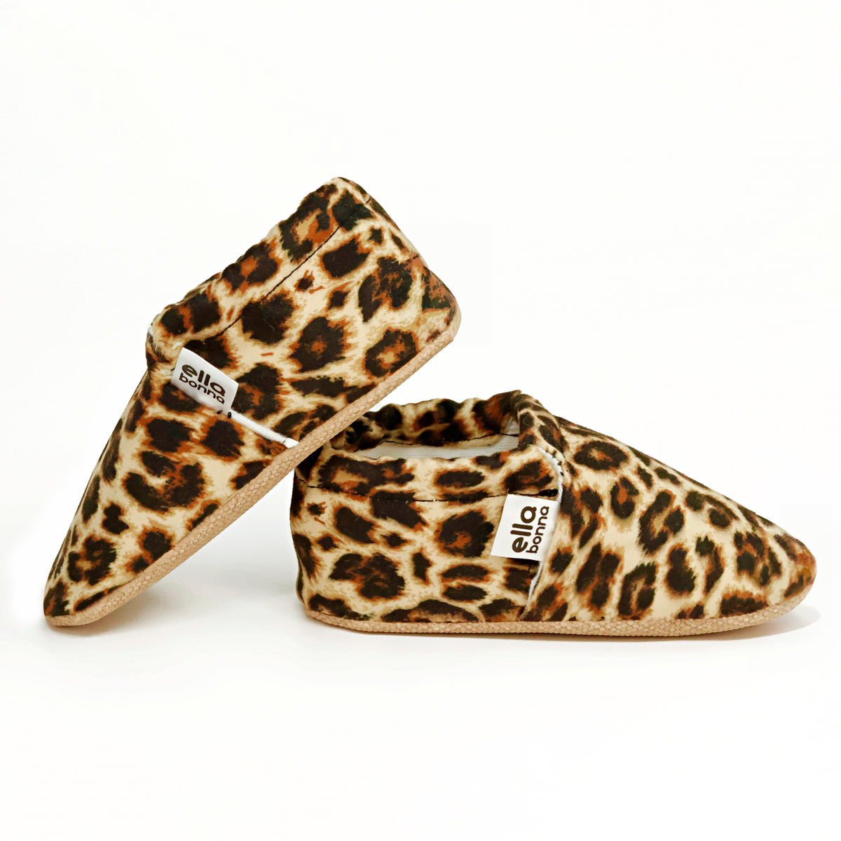 Side views of tan slip-on baby moccasins with brown-and-black leopard spots on a white background.