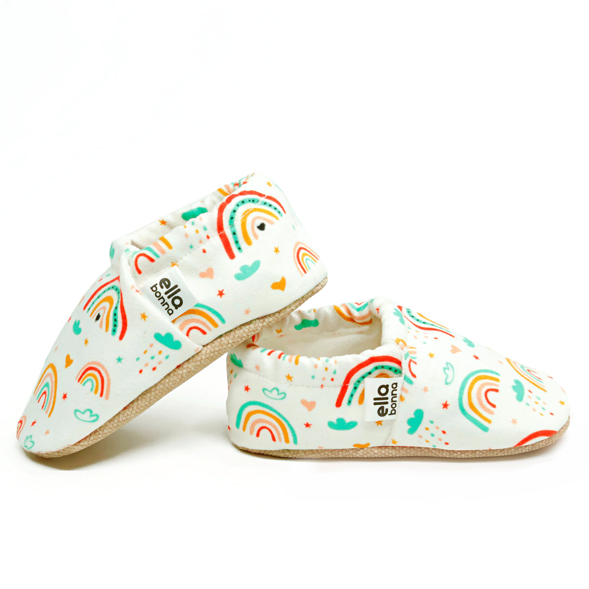 Side views of cream slip-on baby moccasins with colorful rainbow print on a white background.
