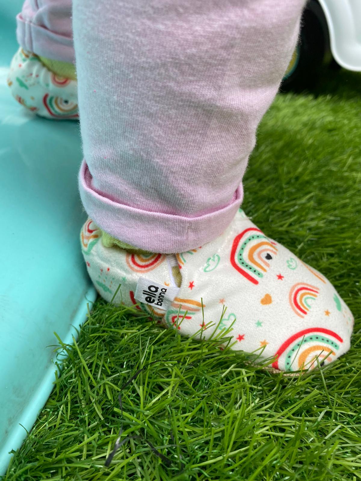 Close-up of a rainbow-print moccasin worn beside a slide on grass.