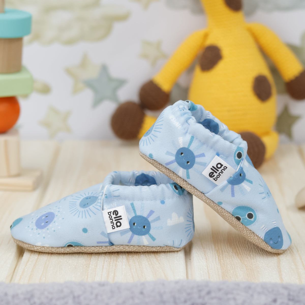 Light blue slip-on baby moccasins with blue sun and moon print arranged together to show the sides and uppers.