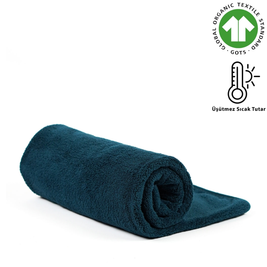 Rolled teal fleece blanket with GOTS badge and warmth graphic.