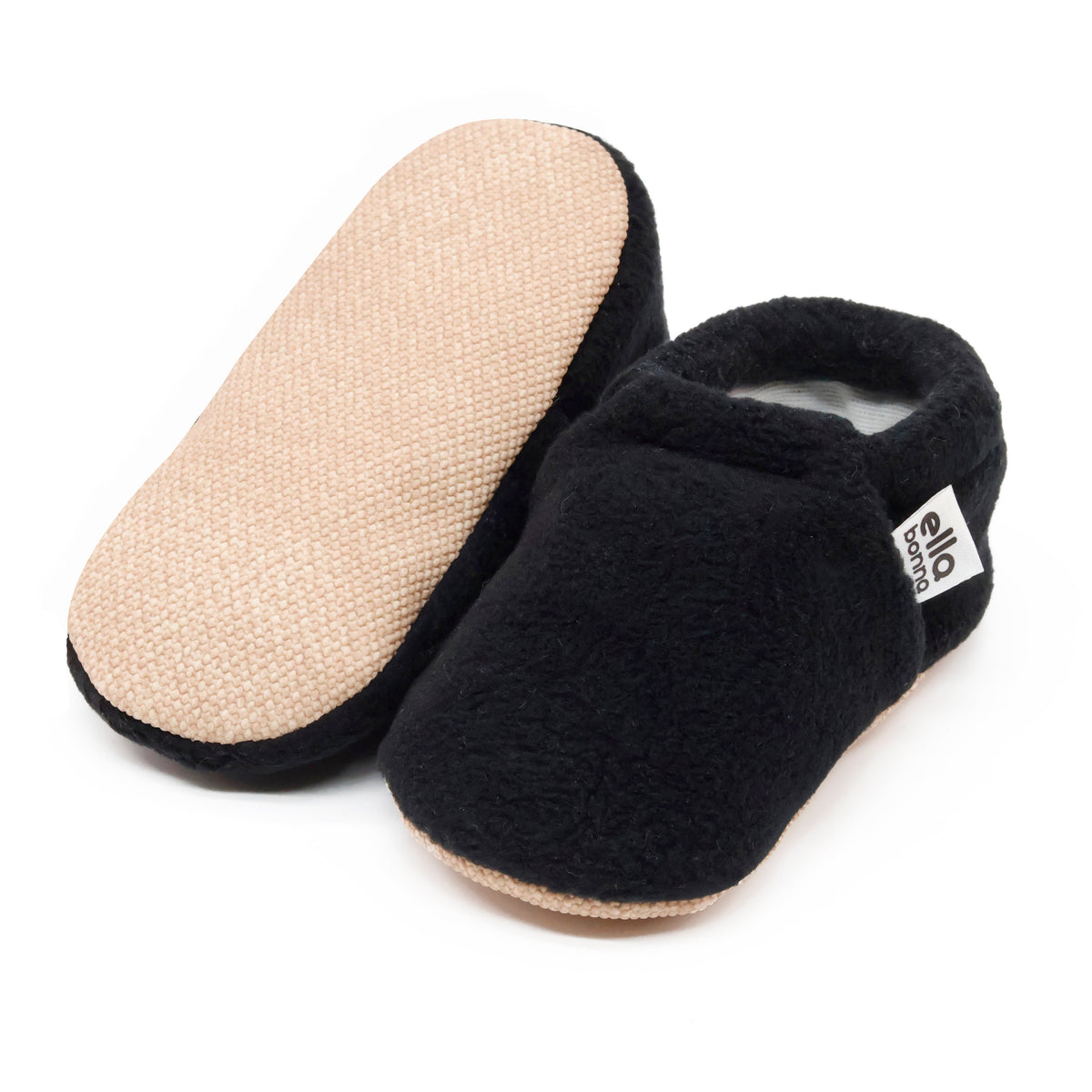 Black fleece slip-on baby moccasins with tan soles, with one sole facing the camera on a white background.