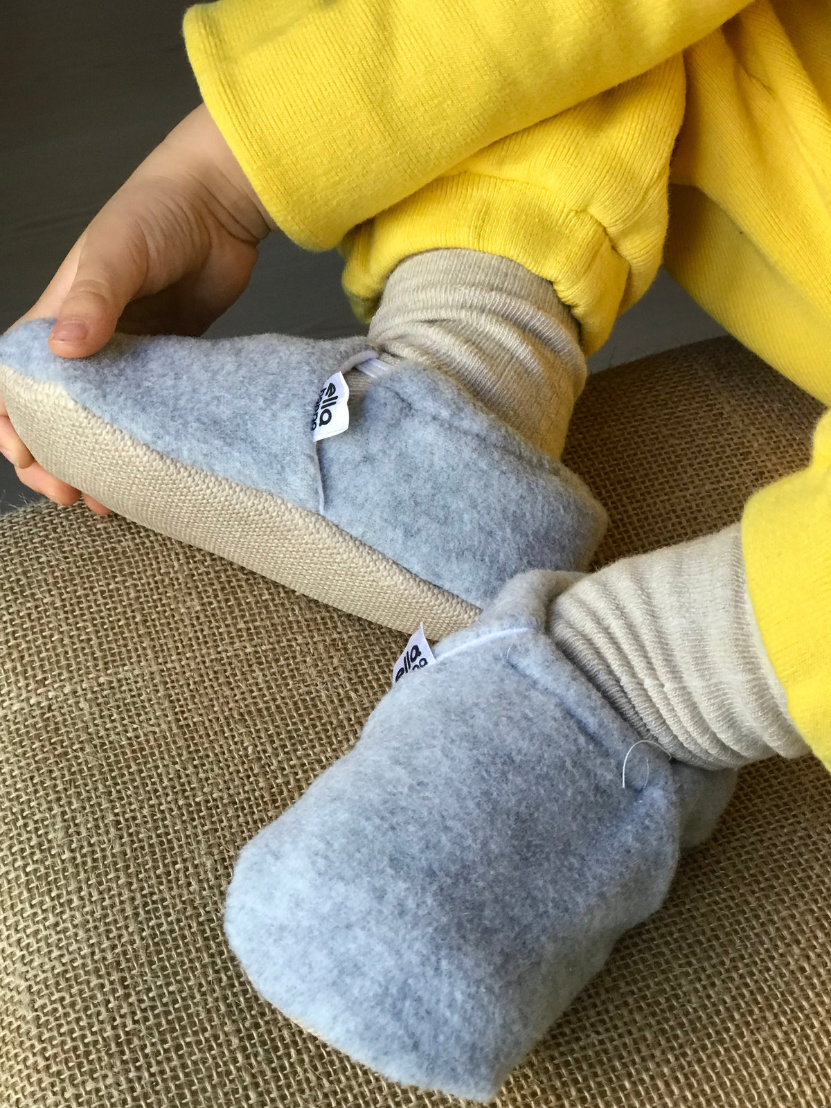Close-up of gray fleece moccasins worn with a yellow outfit.