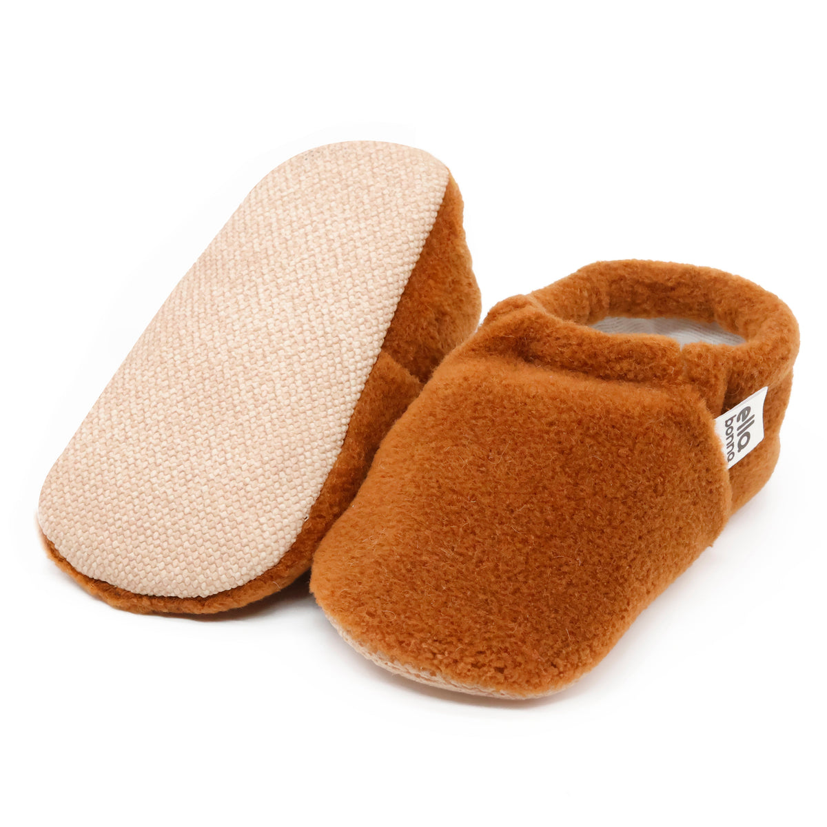 Warm brown fleece slip-on baby moccasins with tan soles, with one sole facing the camera on a white background.