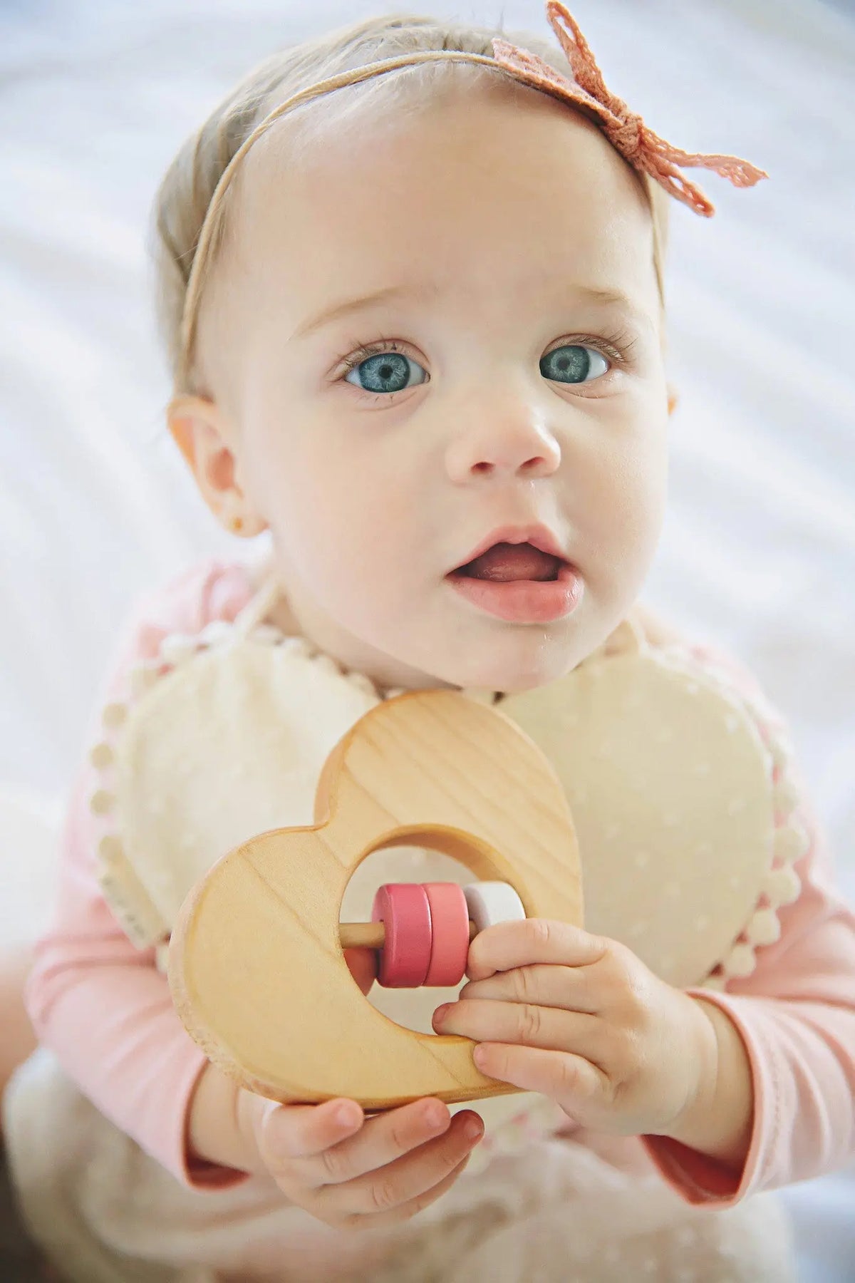 Lifestyle photo showing a wooden baby rattle with a child