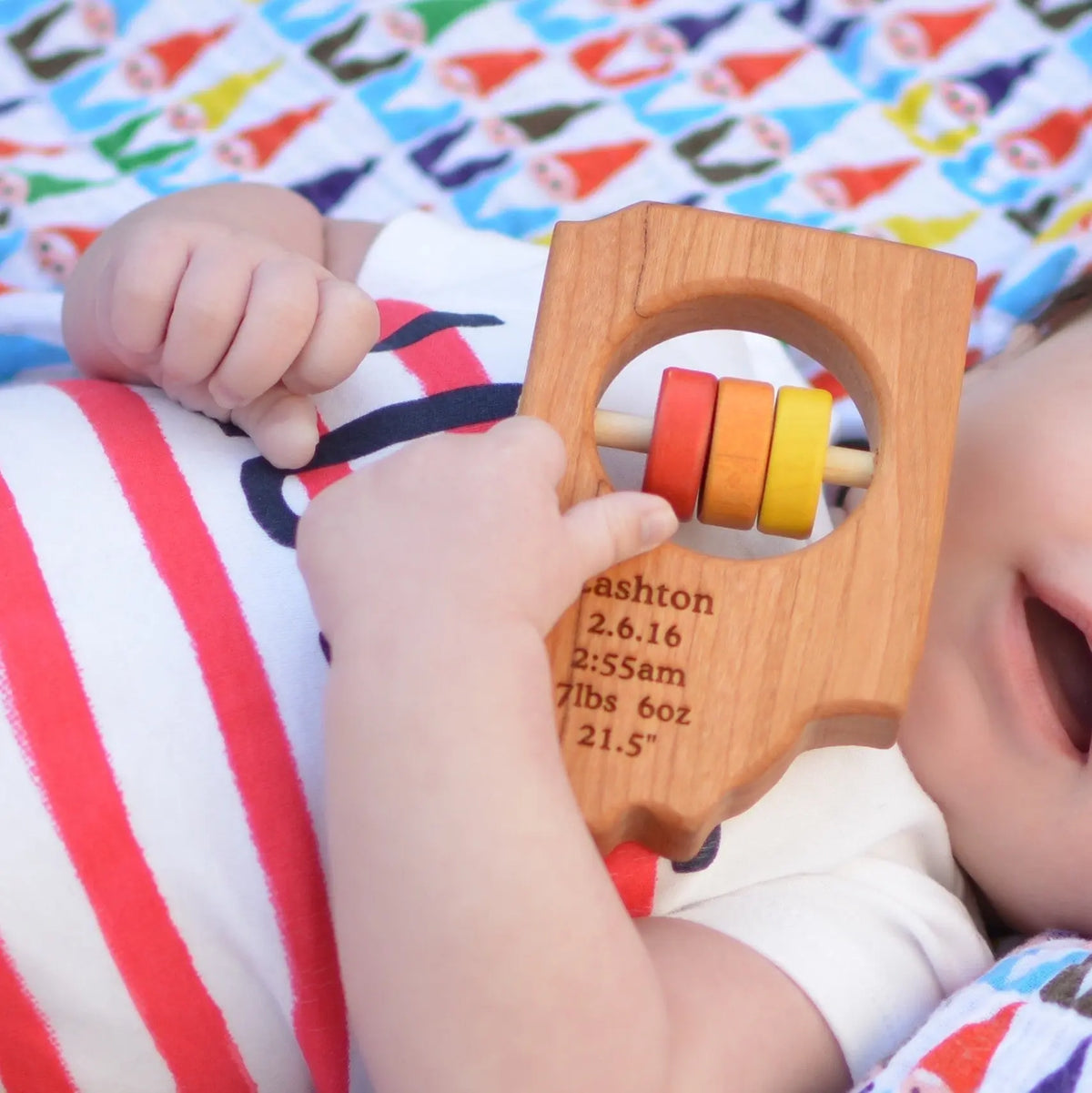 Lifestyle photo showing a wooden state rattle with a child