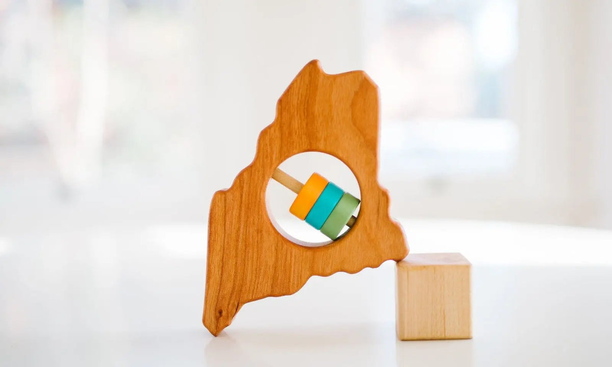 Bannor Toys Maine State Wooden Baby Rattle, showing state-shaped cherry-wood body and colored rattle discs