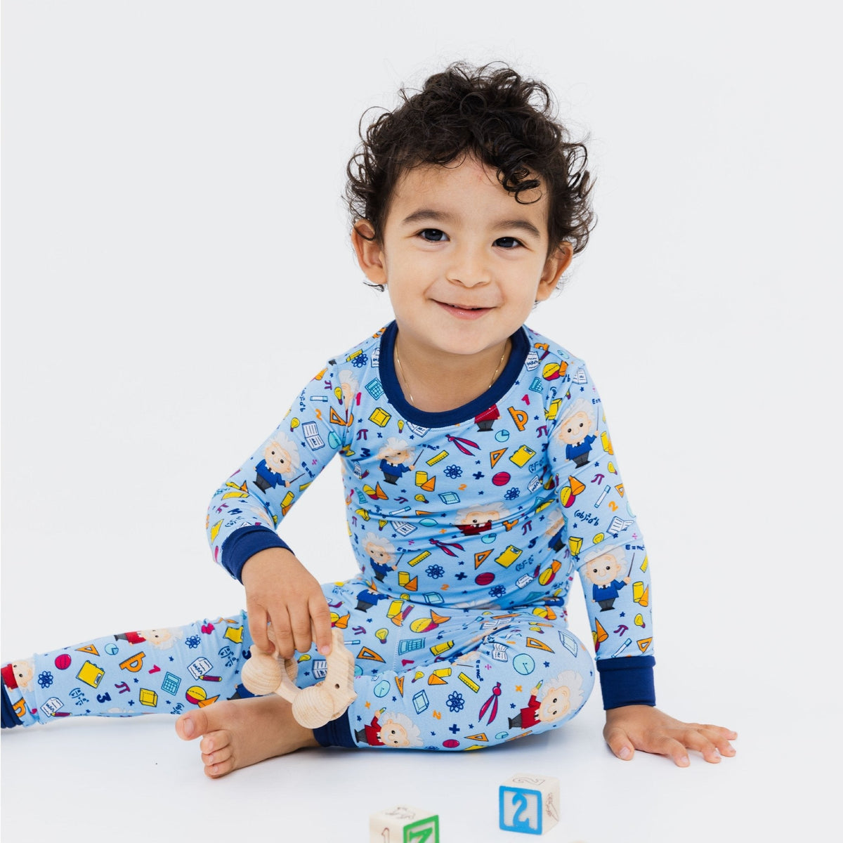 Child seated with toys while wearing Bam & Stitch Mathematical Marvel Long Sleeve Pajamas.
