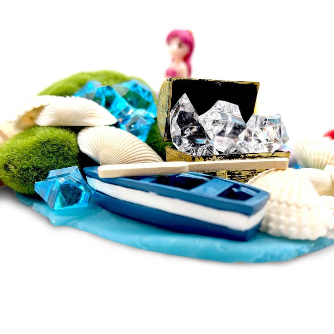 Treasure chest filled with clear gems beside a blue toy boat and shells
