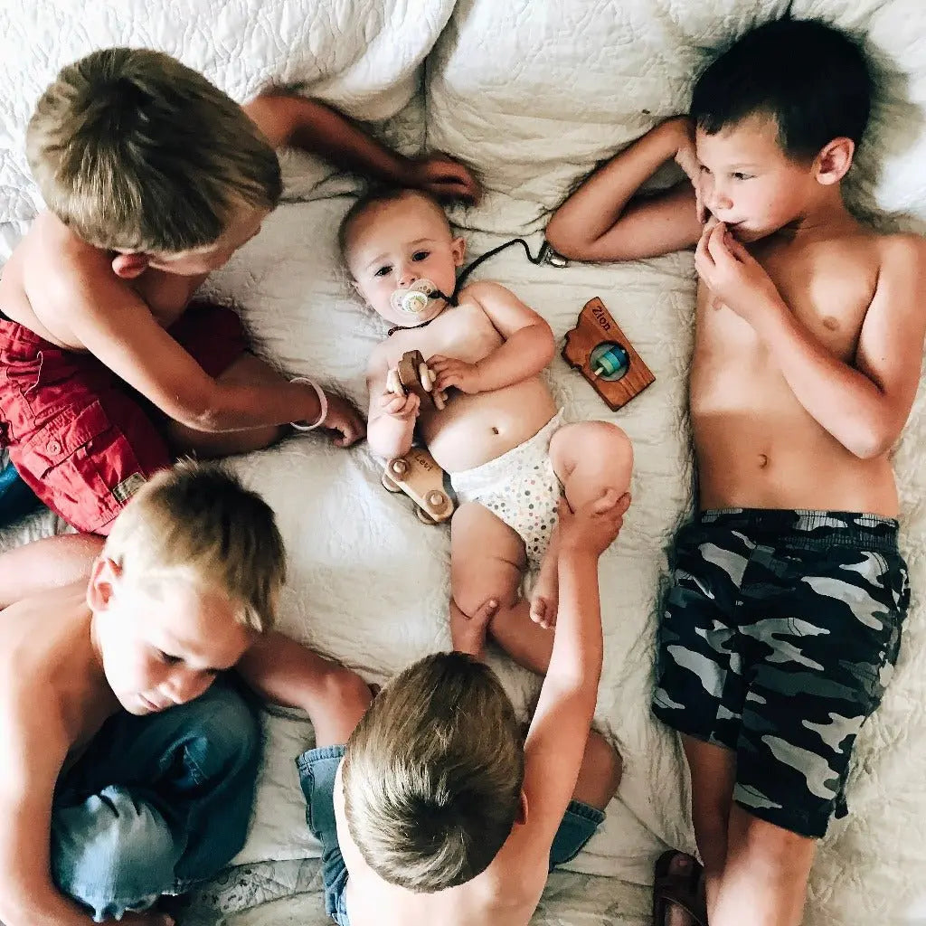 Lifestyle photo showing a wooden state rattle with a child